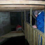 interior of building with new wooden supports, two men and a woman visible in background